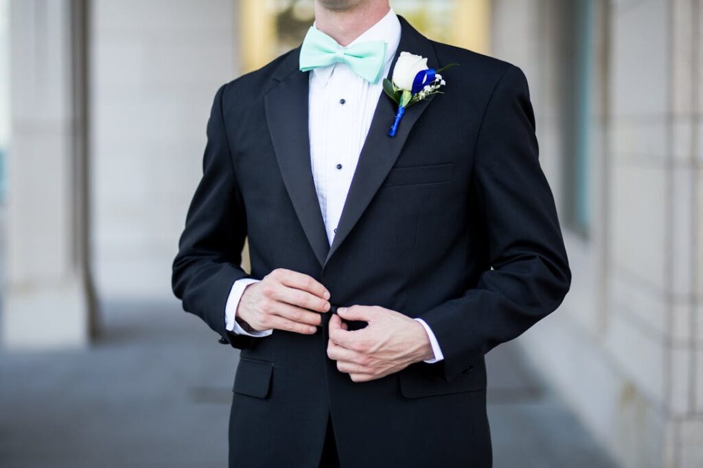 A man wearing a traditional black tuxedo with baby blue bowtie.