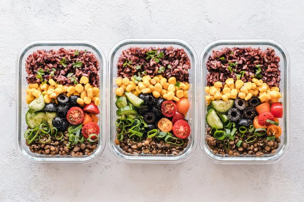 Three storage containers full of meal prepped recipes for muscle gain
