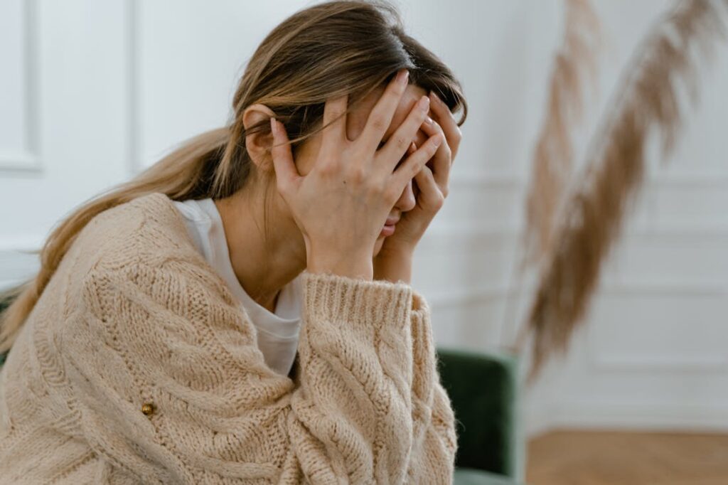 An upset woman holding her head in her hands. Using these relapse prevention tips can help you stay sober.