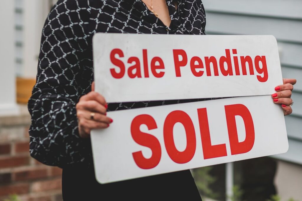 A woman holding a sale pending sold sign. Use these tips when selling your home as is.