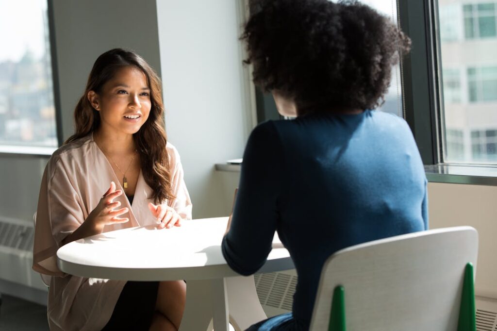 Two women talking at a table while working on developing psychic skills