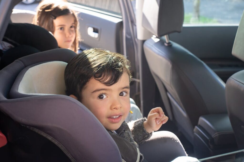 Two little kids getting in their car seats in the back of the car after their parents learned how to choose the right family-friendly vehicle.