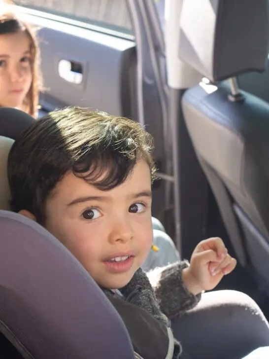 Two little kids getting in their car seats in the back of the car after their parents learned how to choose the right family-friendly vehicle.