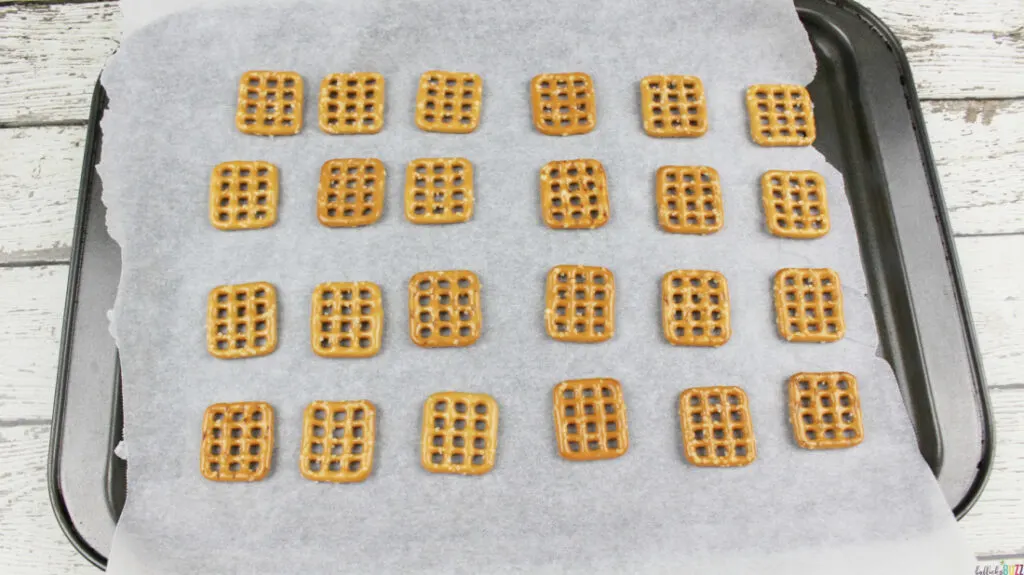 Pretzel squares laid out in rows on a parchment paper lined baking pan