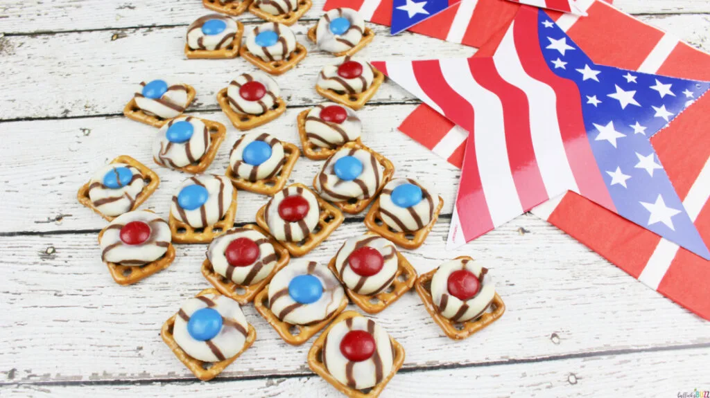 Finished Patriotic Pretzel Hugs laid out on a white background next to paper stars with the American flag on them.