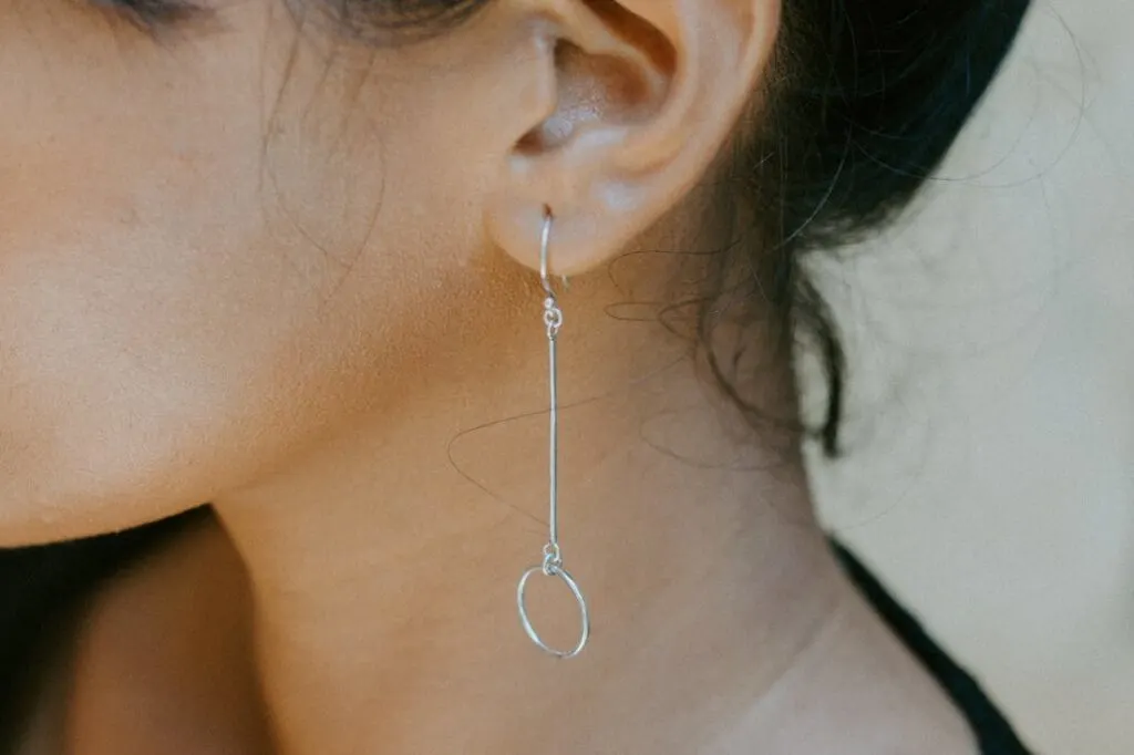 Picture of a woman's ear with a long earring. Use these common ear cleaning tools to safely and effectively clean your ears.