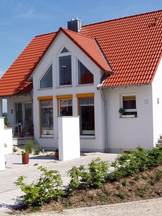 A white house with beautiful red tile roof is one example of the benefits of upgrading your roof