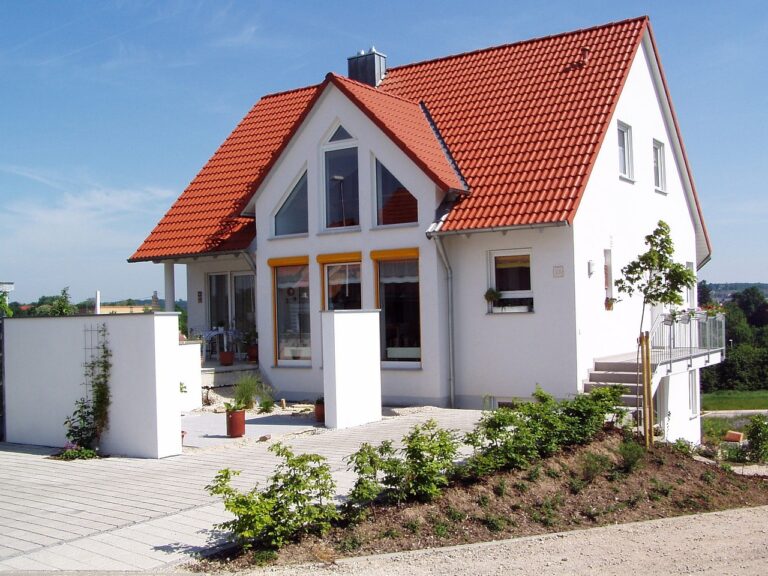 A white house with beautiful red tile roof is one example of the benefits of upgrading your roof