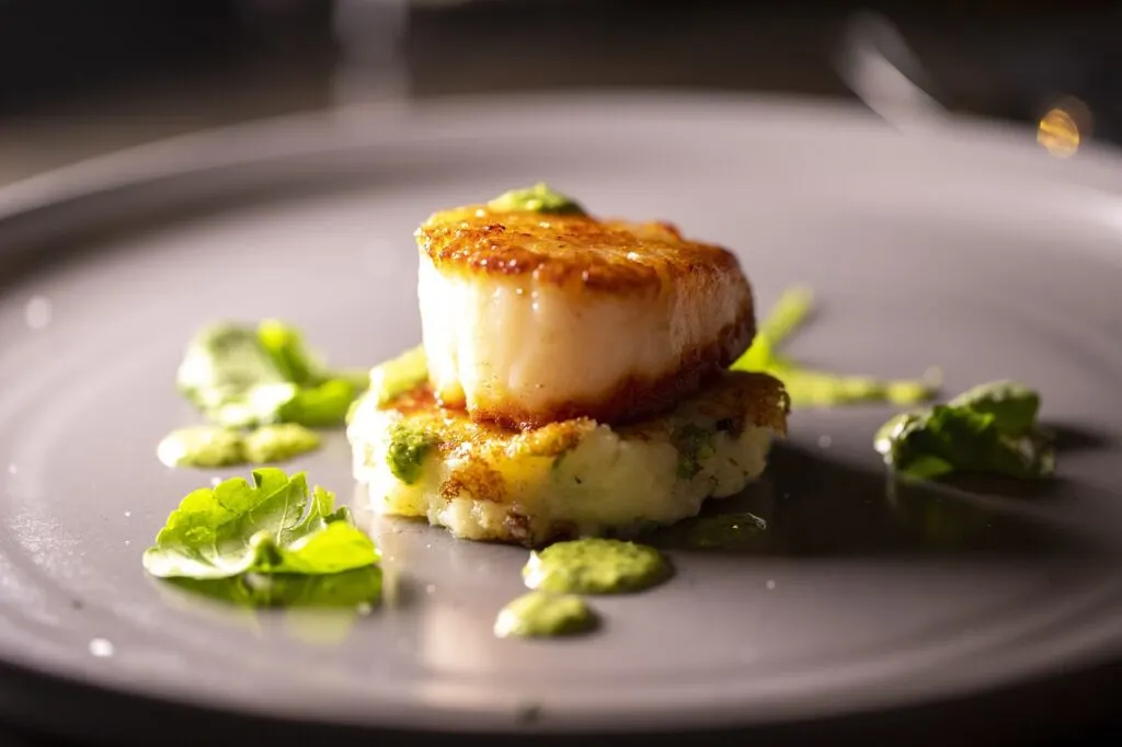 Plated scallops on a purple plate
