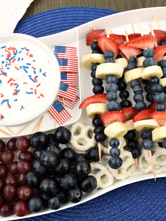 Fruit kabobs and a bowl of fruit dip on a flag shaped tray