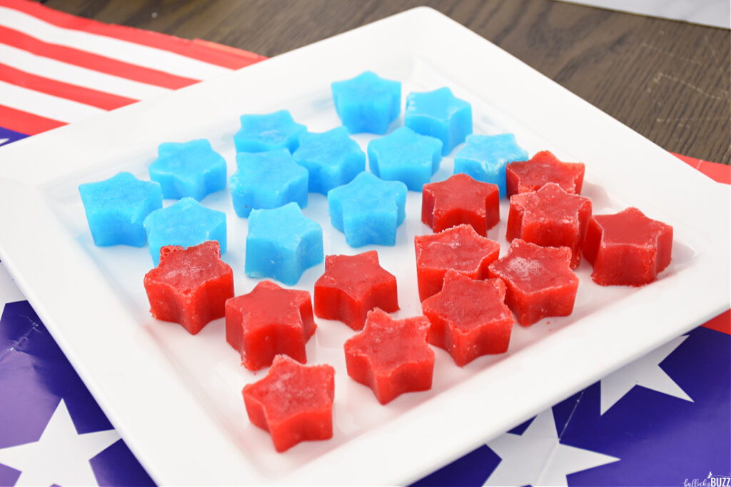 Red and blue star-shaped Jell-O ice cubes removed from molds and placed on a white plate