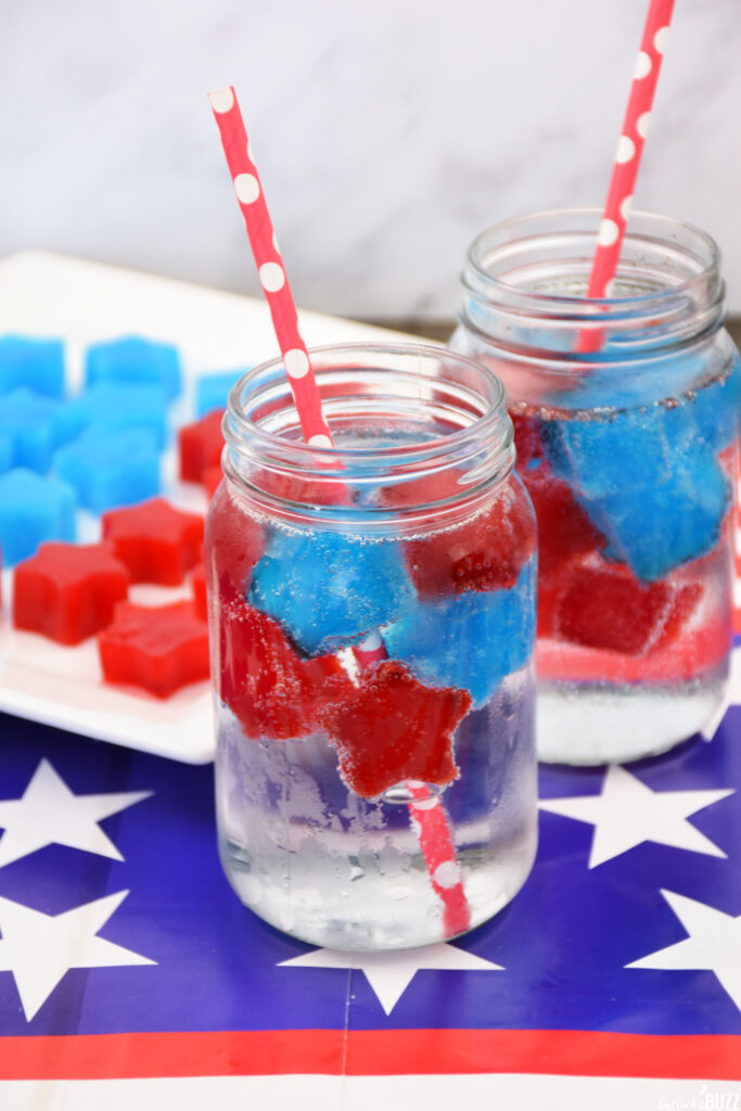 Close up of star shaped Jell-O ice cubes in a glass with lemon lime soda and a paper straw