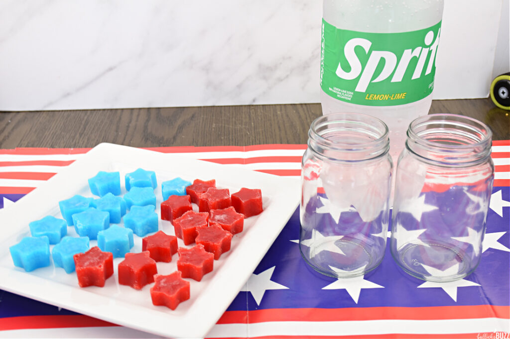 finished Jell-O ice cubes on a white plate with a bottle of lemon lime soda and two glasses next to it