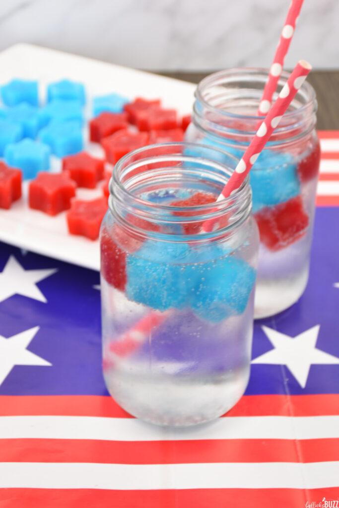 Two glasses filled with red and blue jell-o ice cubes and lemon lime soda