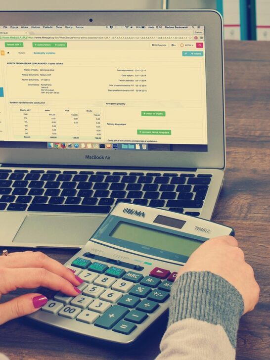 A man working on his calculator and laptop managing finances after a personal injury