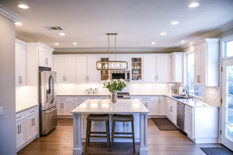 A beautiful white kitchen with several types of lights as an example of architectural lighting in a home.