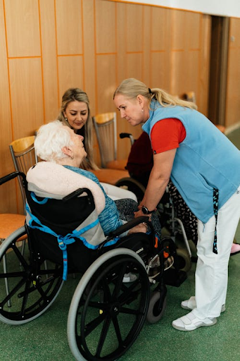 An elderly person in a wheelchair talking to a nurse. Learn about the benefits of at-home assisted living for seniors.