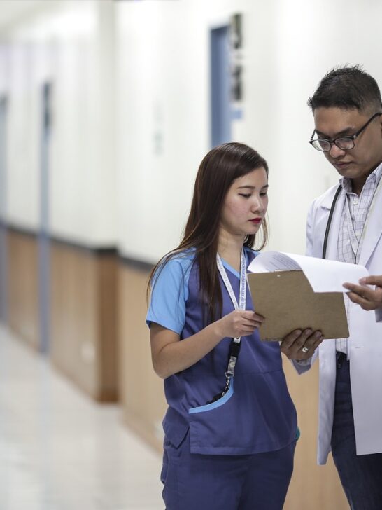 A doctor and a woman who choose a career as a physicians assistant are conferring in the hallway of a hospital