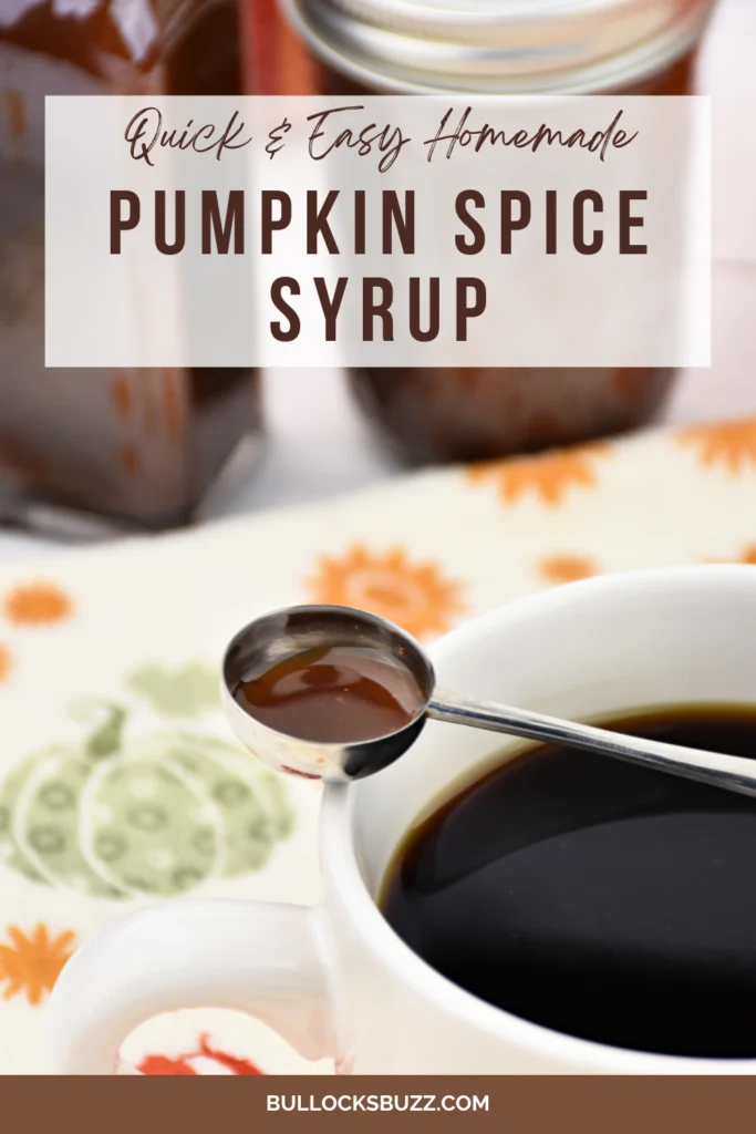 A spoon full of homemade pumpkin spice syrup balanced across a cup of coffee with two bottles of the fall syrup sitting in the background