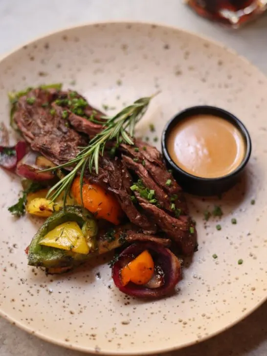 A perfectly cooked lamb roast arranged nicely on a plate. Part of cooking the perfect roast is serving it aesthetically.