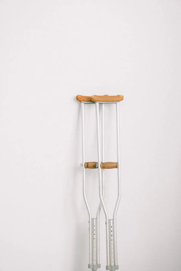 A pair of crutches against a white wall. Crutches are often part of Key Steps to Improving Health Post-Injury
