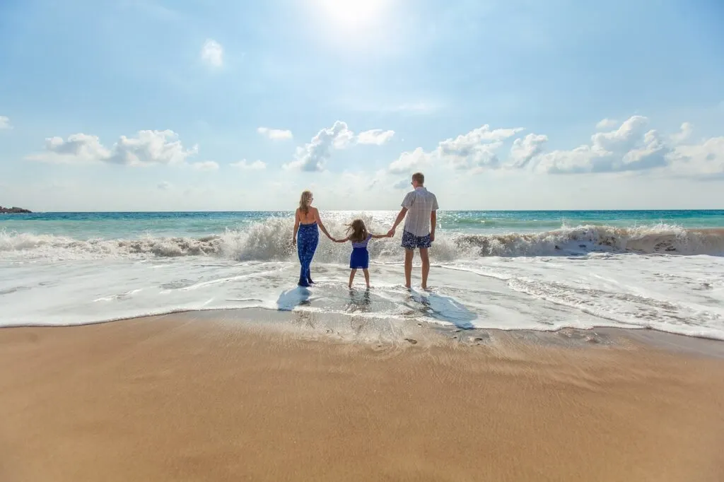 A family walking hand in hand on the beach after planning the perfect family vacation.