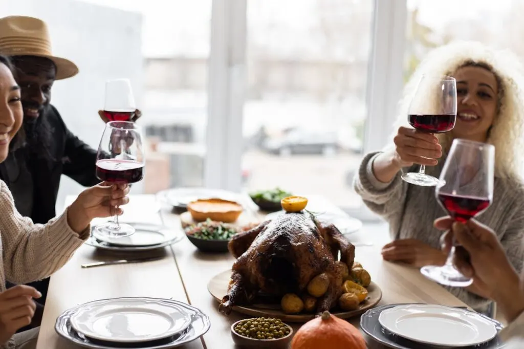 A group of friends toasting each other at the table before enjoying a roasted turkey