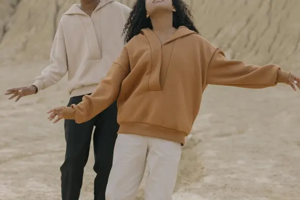 A man and woman standing in the sand showing off their fashionable clothes