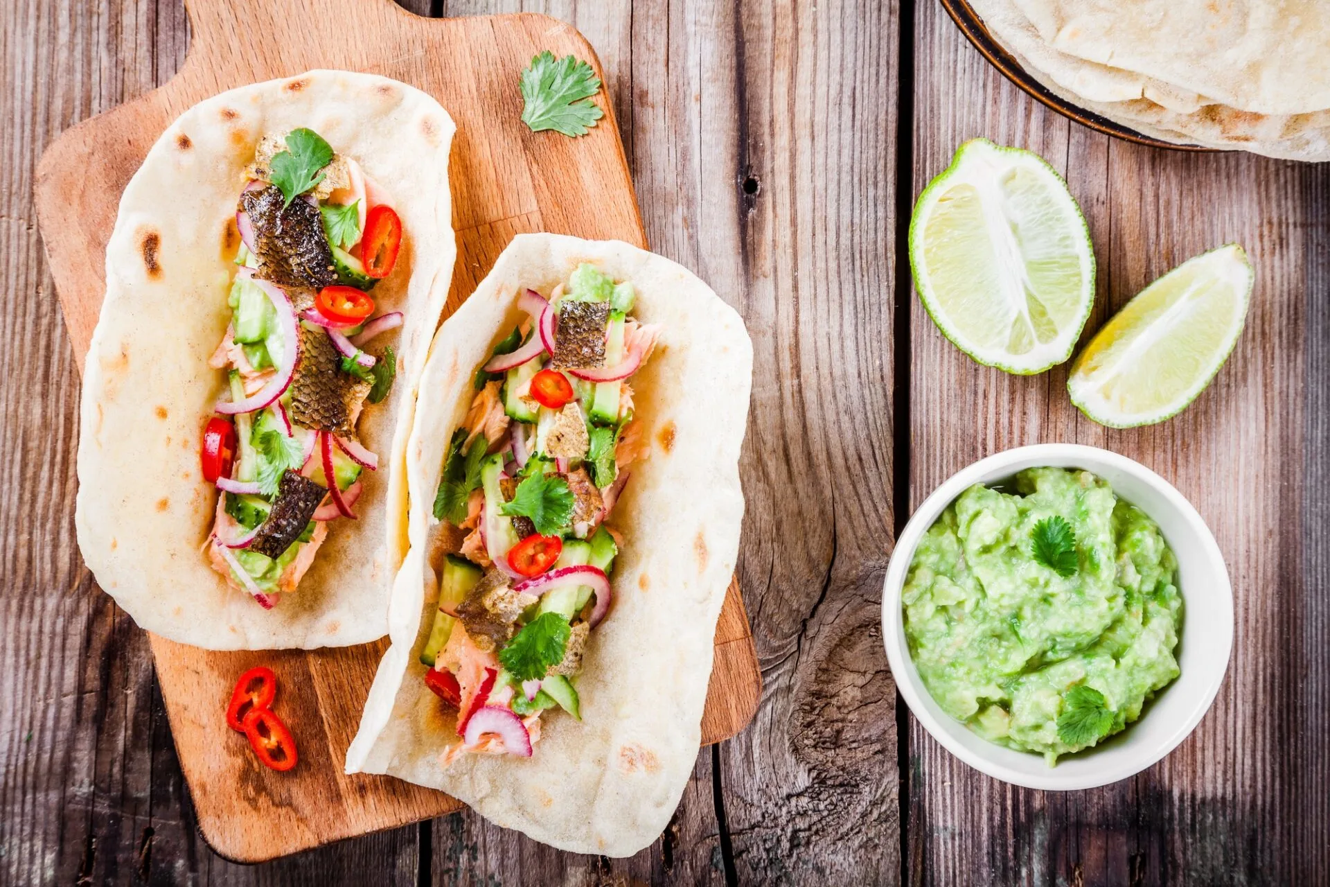 Grilled Salmon Tacos on a cutting board with a bowl of guac. Salmon Tacos are on of the most popular and easy to make salmon dishes