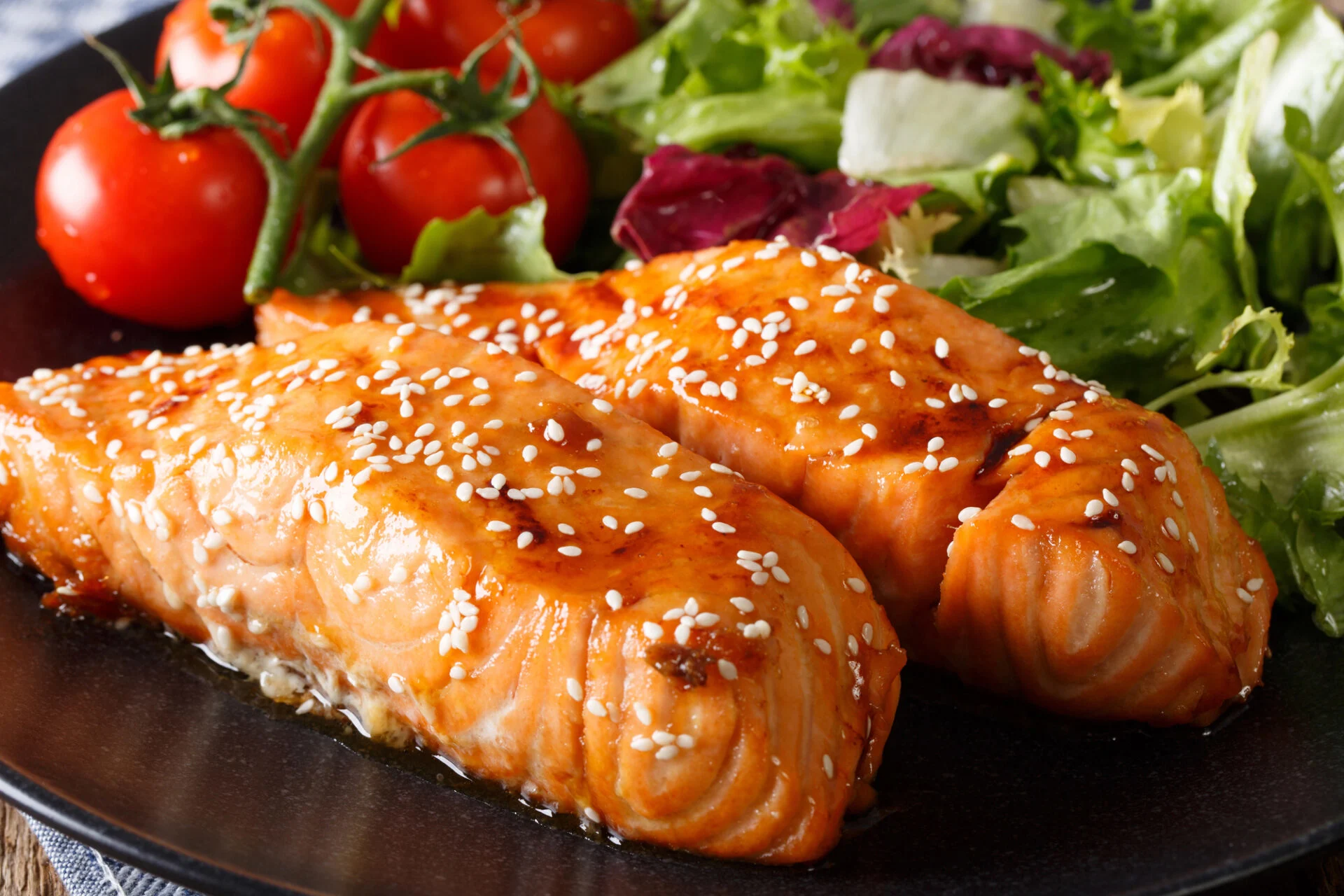 Maple Soy Glazed Salmon on a plate with tomatoes and salad