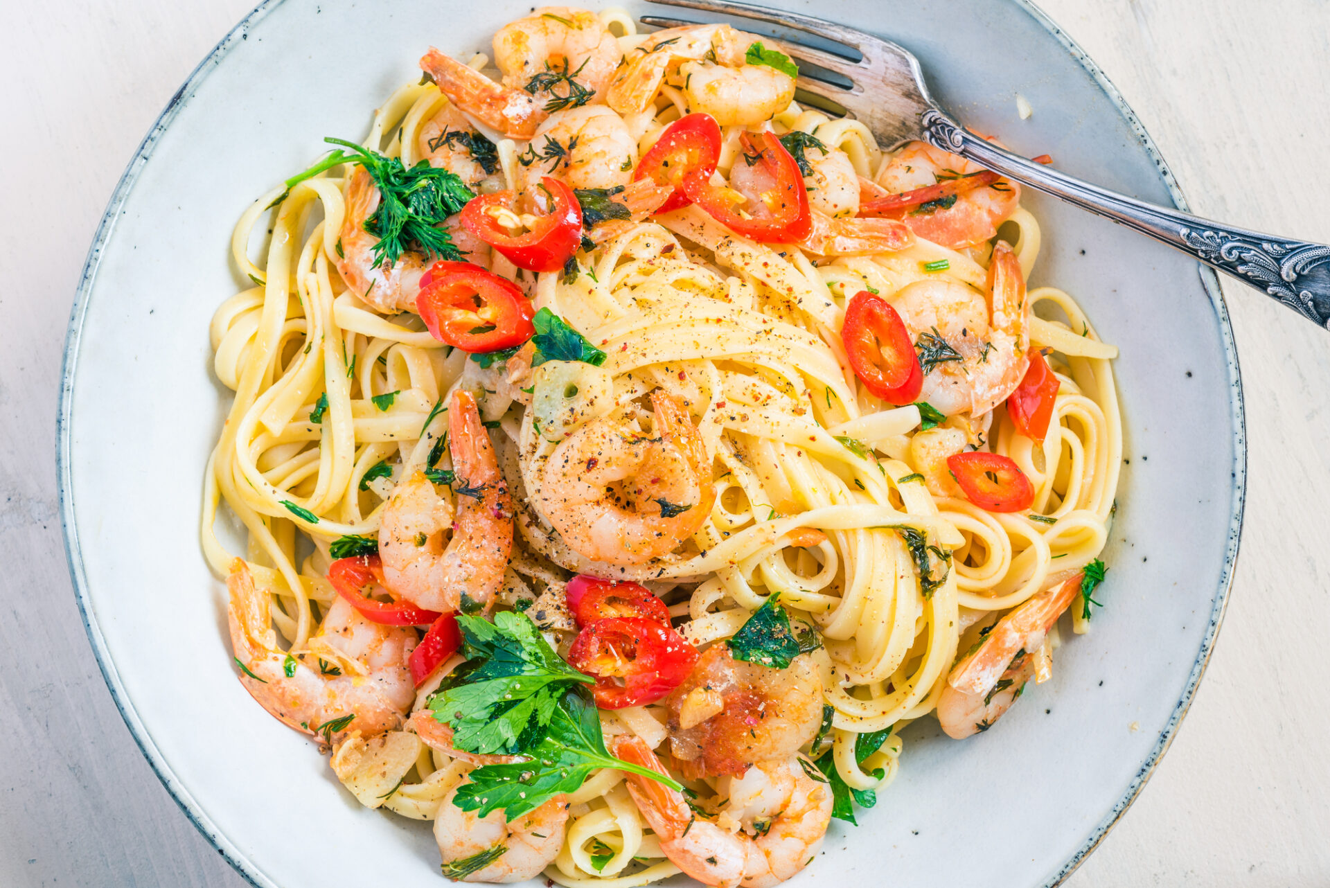 Linguine with shrimps on a rustic plate close-up, top view - traditional Mediterranean pasta with seafood, Italian cuisine.