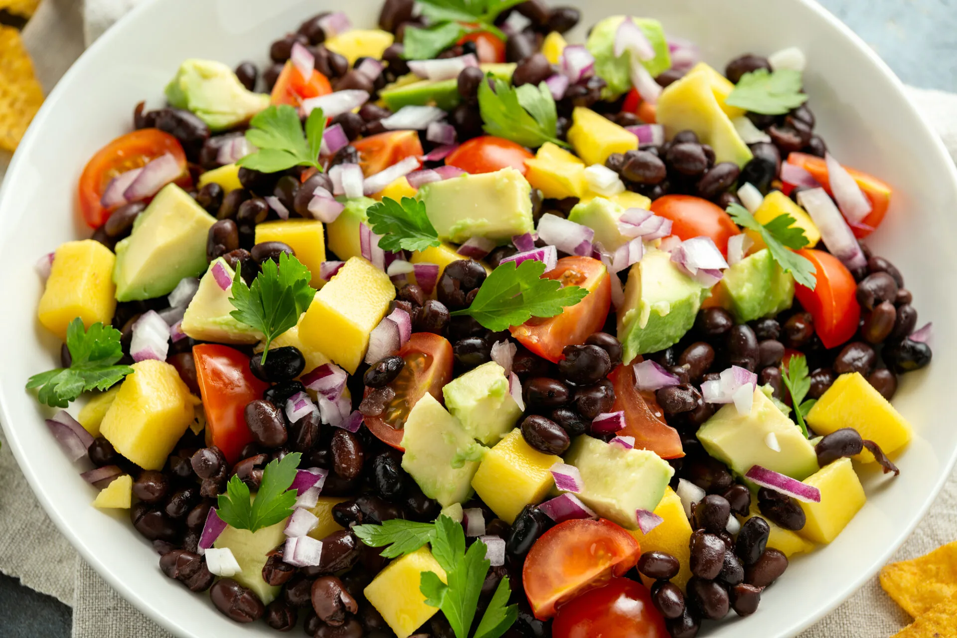 Avocado, mango salad with black bean, tomato, red onion and tortilla chips. healthy food.