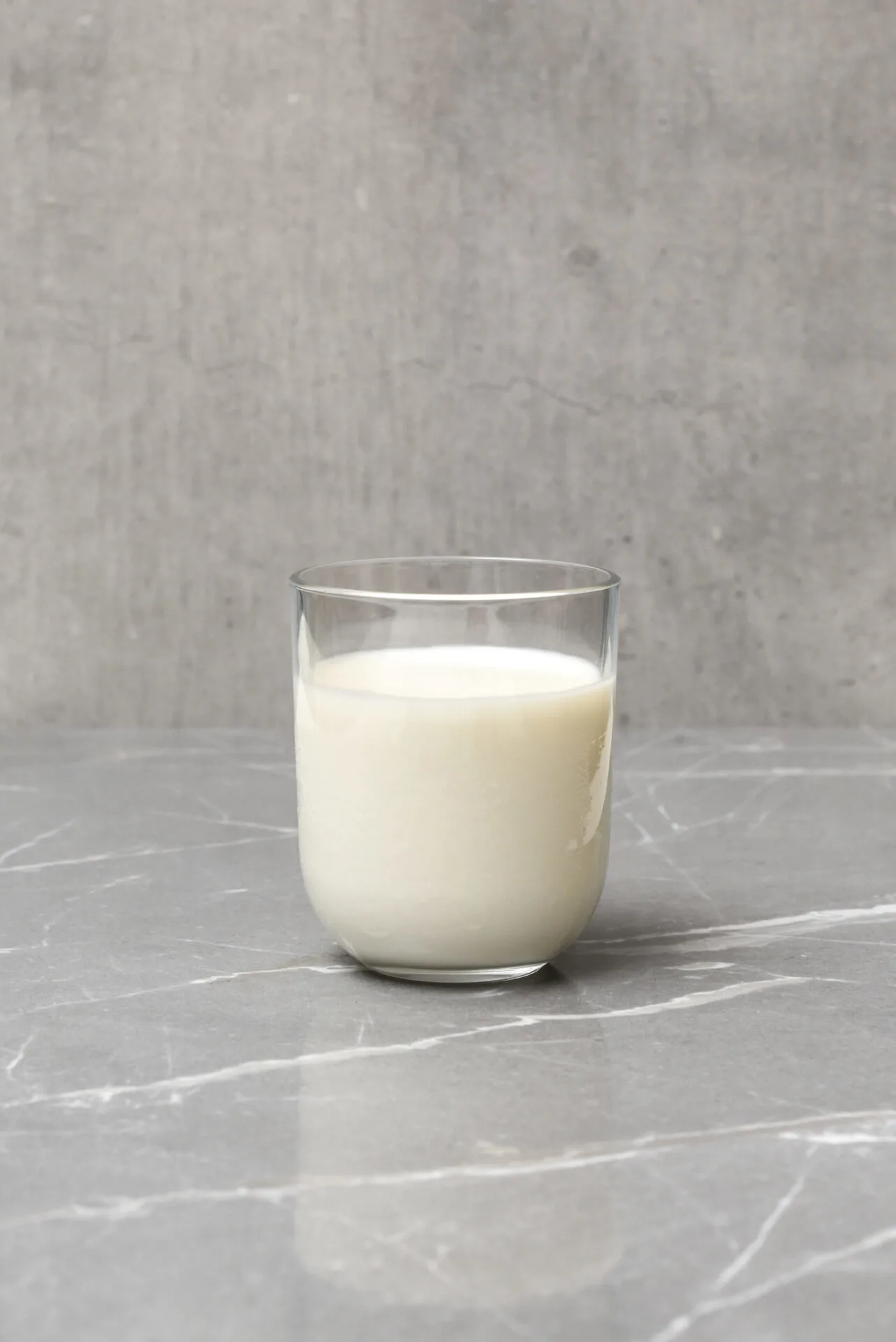 Almond milk in a glass with almond ingredients on table