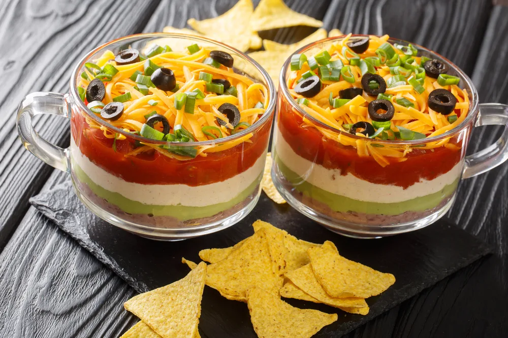 Delicious food appetizer Mexican seven-layer dip salad served with chips close-up on the table. horizontal