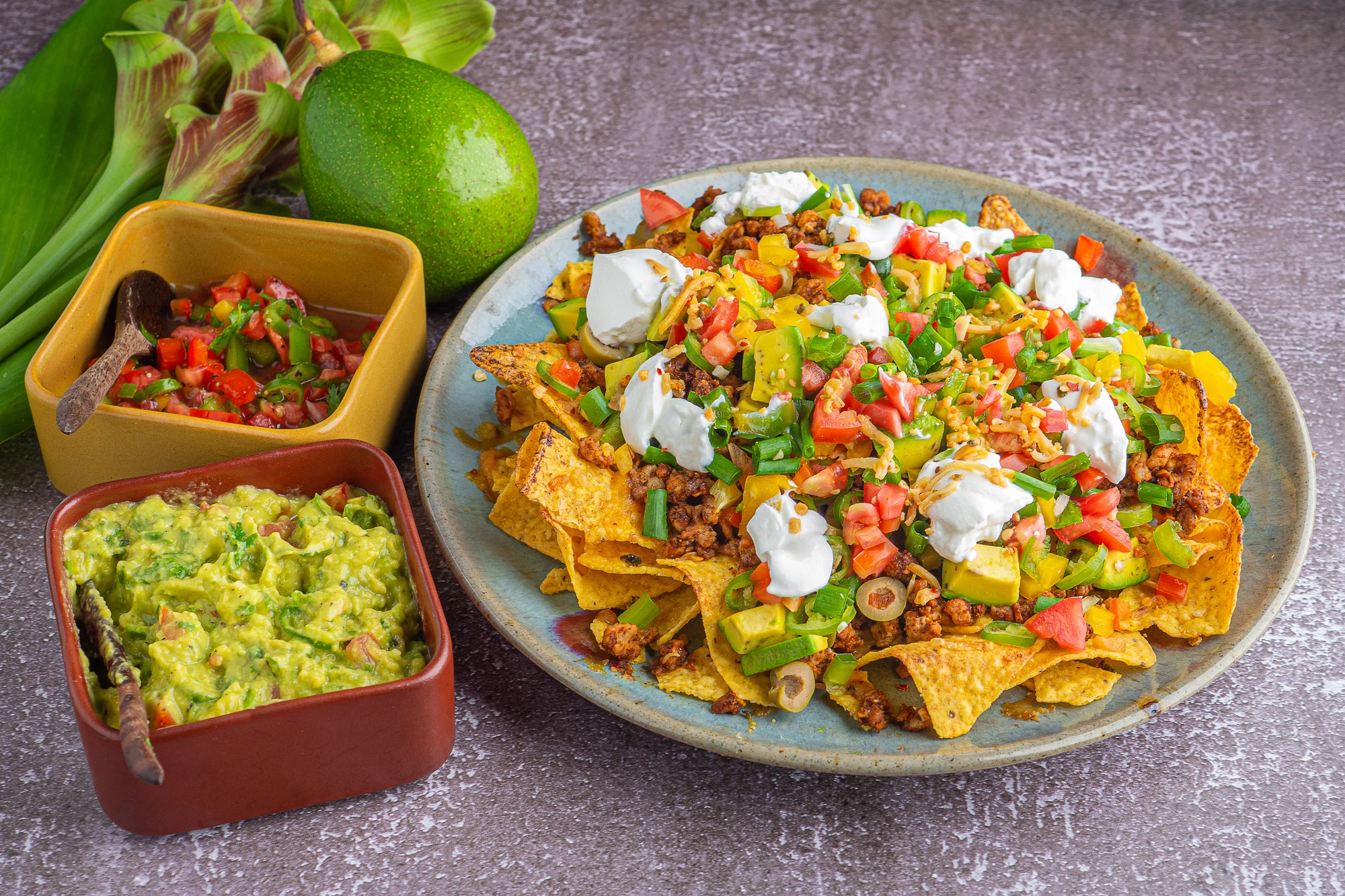 Close-up of loaded minced pork nachos with guacamole and salsa dips. Space for text. Concept of Mexican food