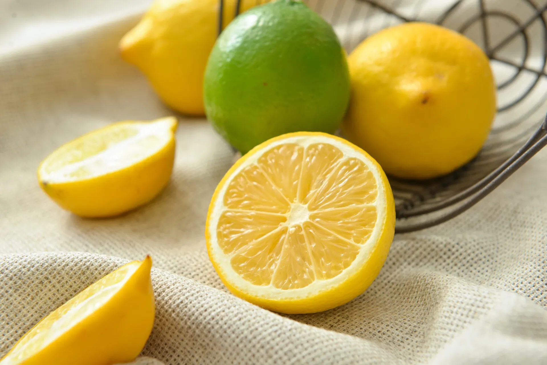 Basket with healthy citrus fruits on light fabric, closeup
