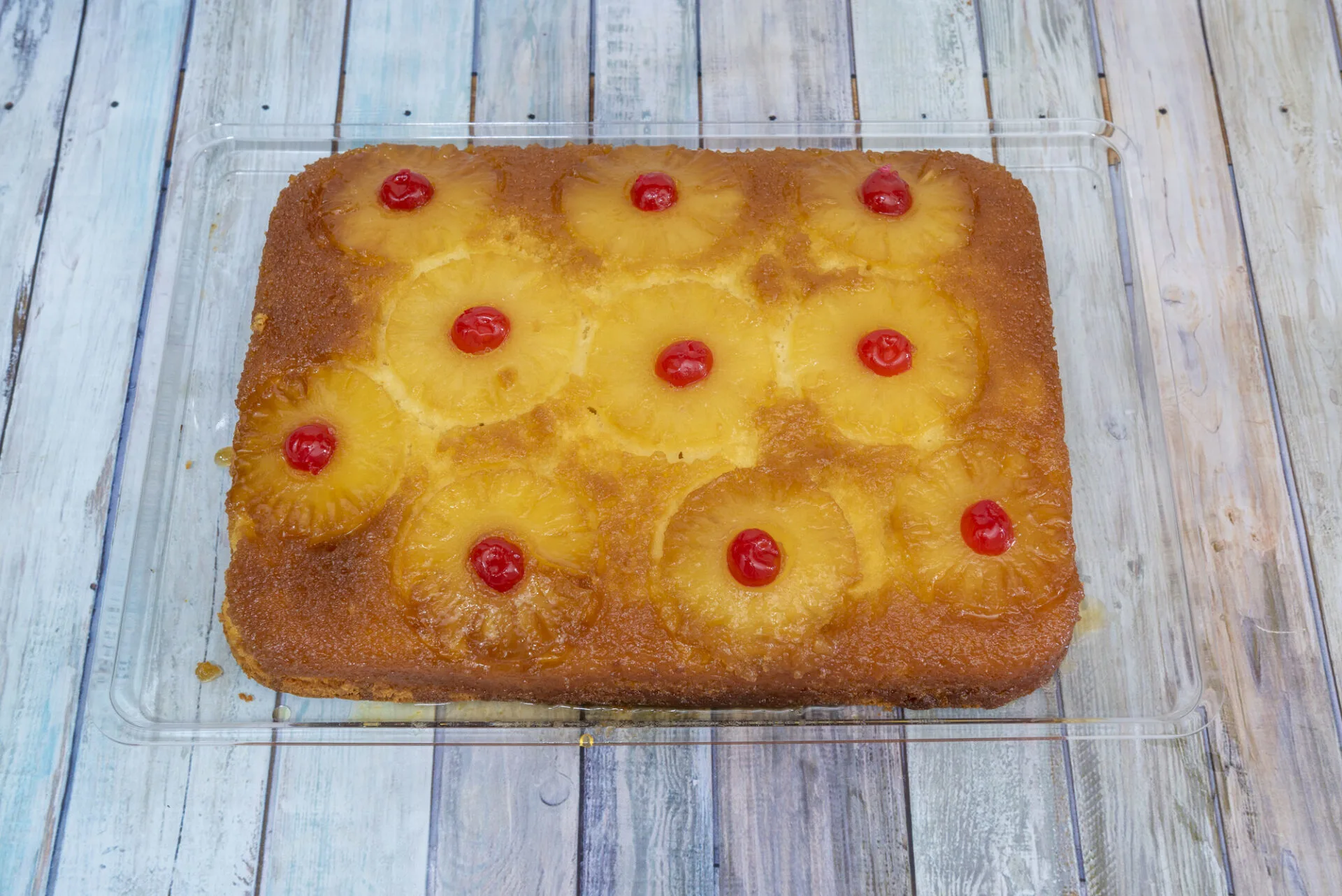 large pineapple tart with candied cherries and roasted pineapple slices on moist sponge cake