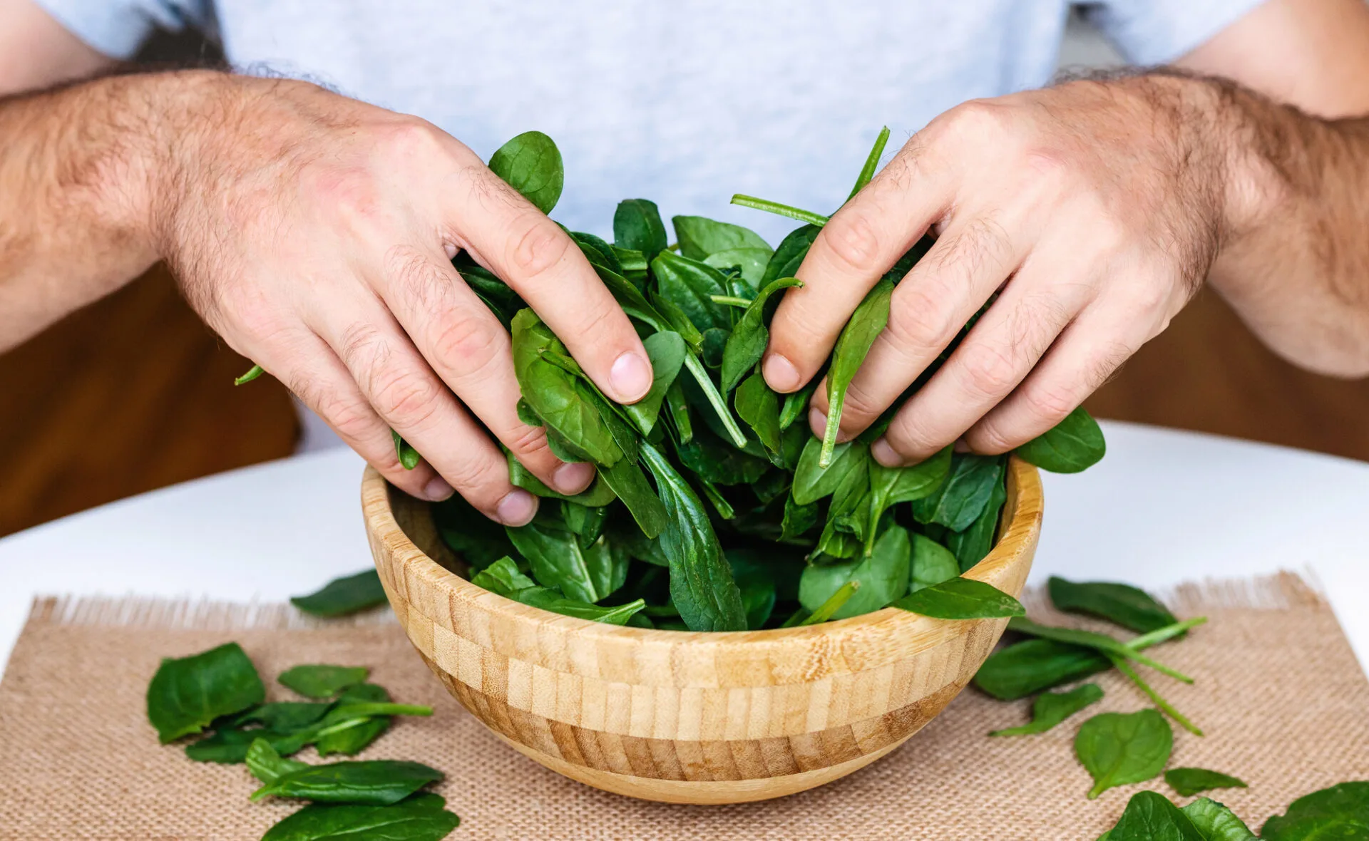 Spinach in male hands. Bowl green spinach.