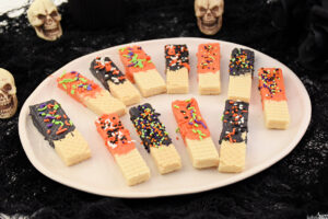 Plate full of orange and black chocolate-dipped cookies for Halloween