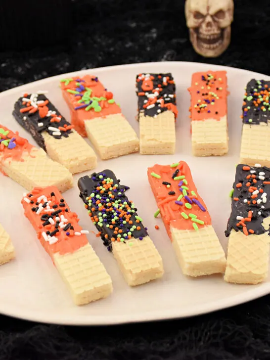 Plate full of orange and black chocolate-dipped cookies for Halloween