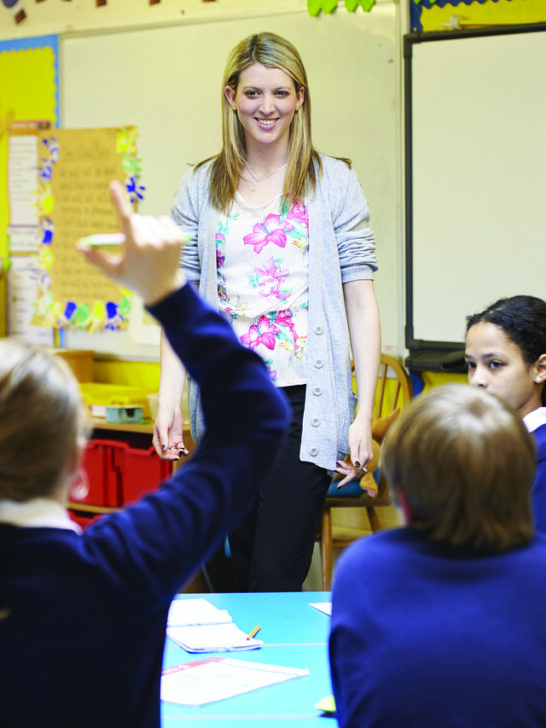 A teacher standing at the front of her room asking questions of her students acting as a professional tutor