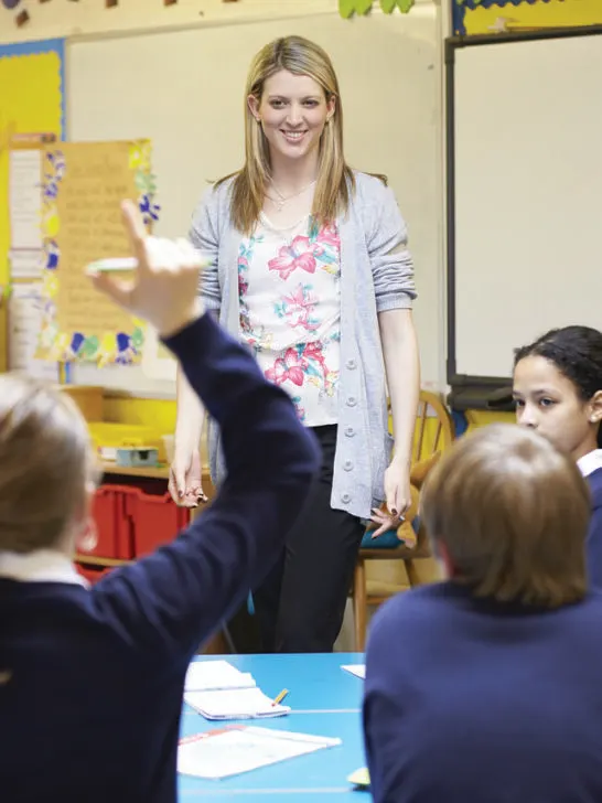 A teacher standing at the front of her room asking questions of her students acting as a professional tutor