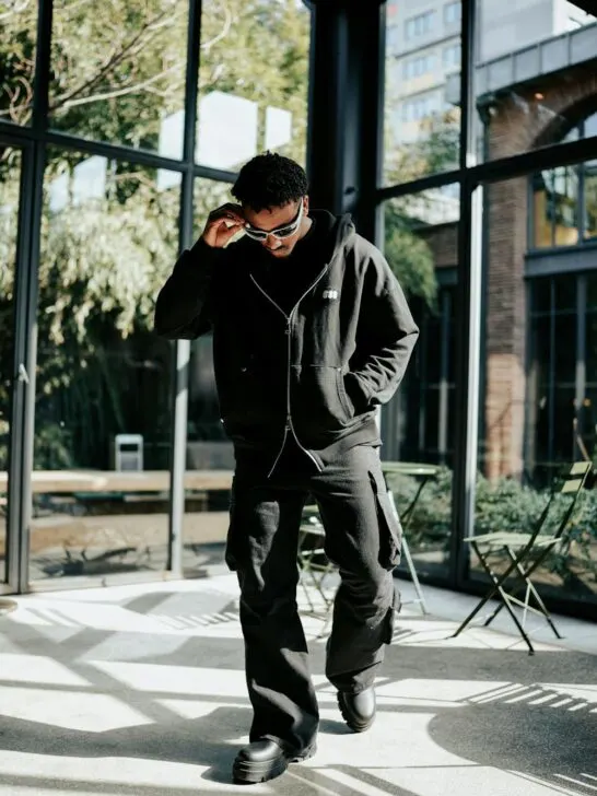 A nicely dressed man wearing cargo pants for men, boots, a jacket and shades.