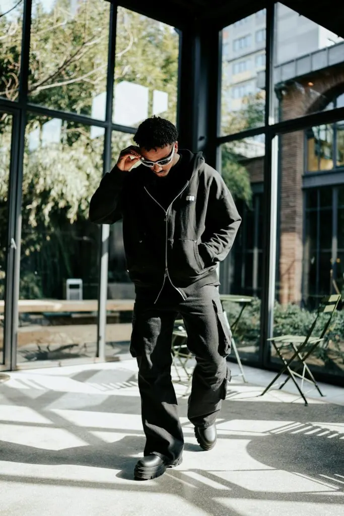 A nicely dressed man wearing cargo pants for men, boots, a jacket and shades.