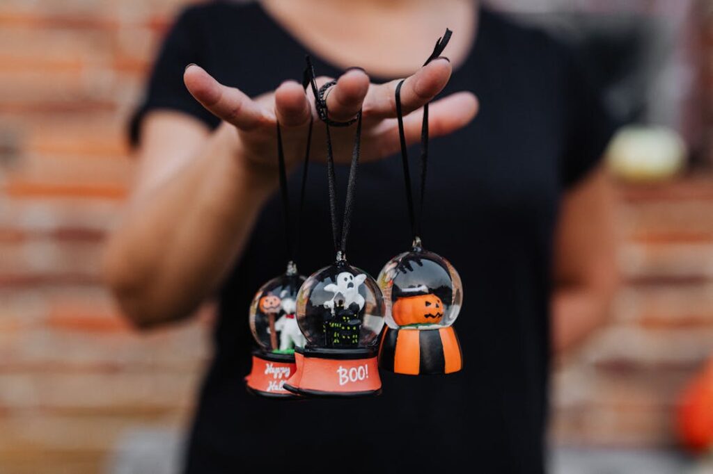 A person holding three tiny Halloween snowglobe party favors in one hand