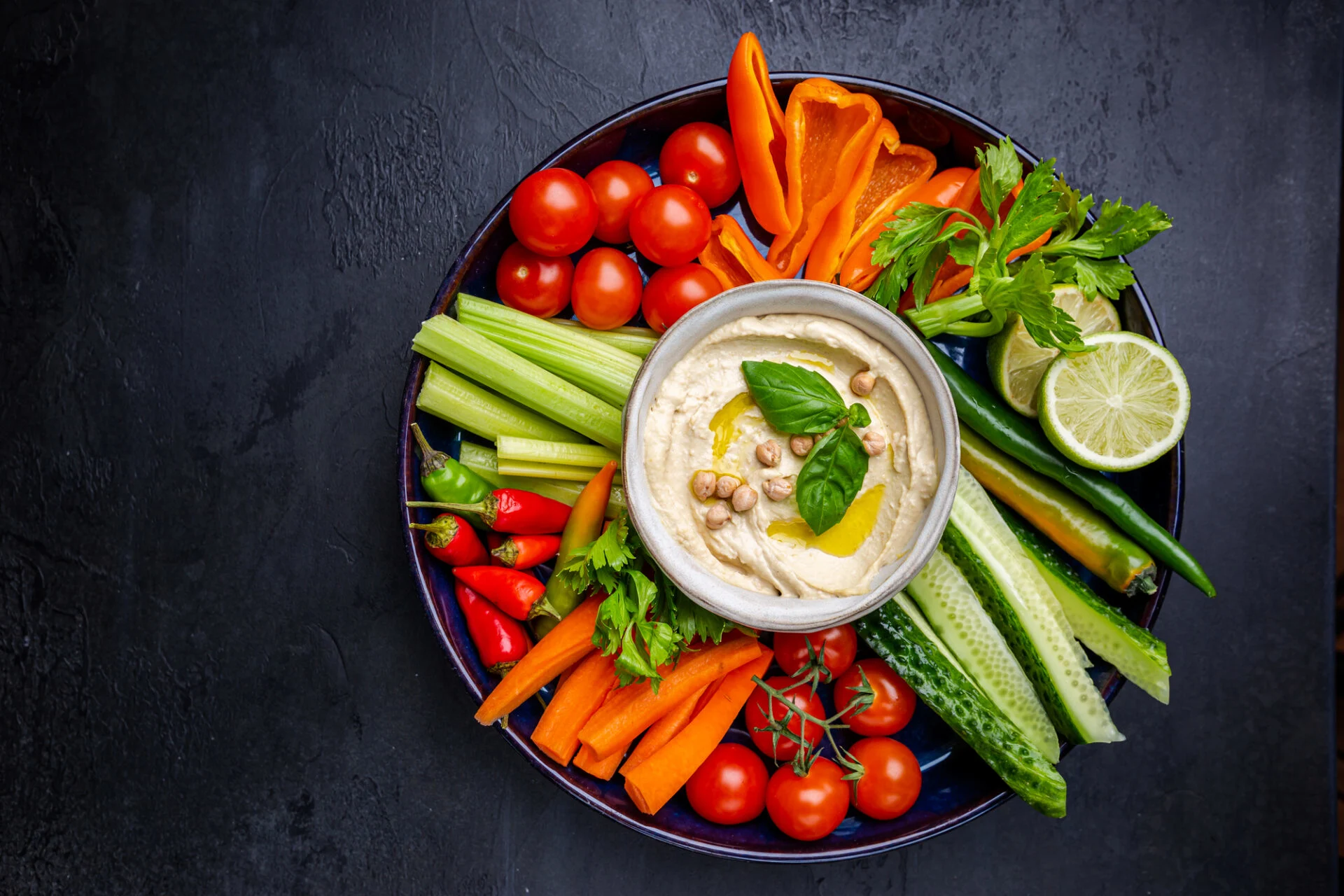 Hummus platter with assorted snacks. Hummus in bowl and vegetables sticks. Plate with Middle Eastern. Party, finger food. Top view. Vegan, hummus dip