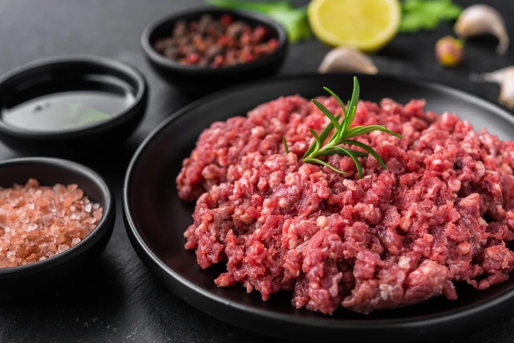 Fresh minced meat ground beef on a black plate against stone background