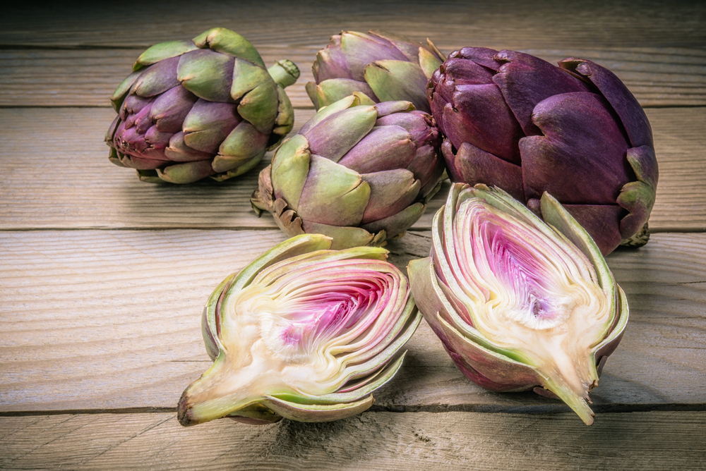 Small artichokes on old wooden table.