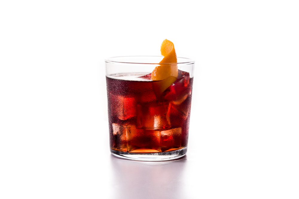 Boulevardier cocktail and orange zest in glass isolated on white background