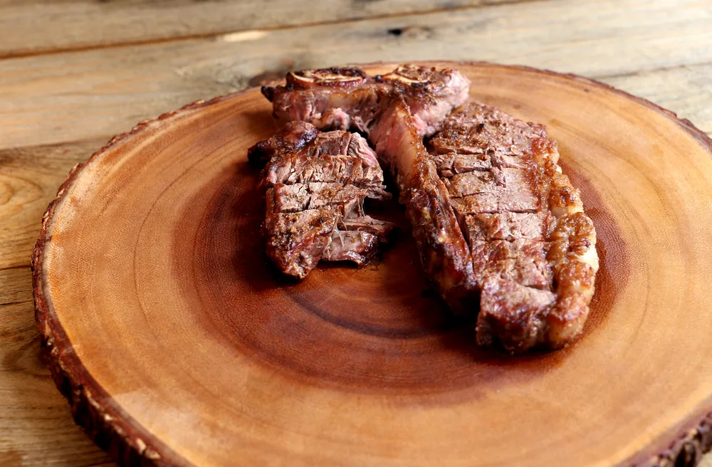 Steak grilled on the grill with bone and two types of meat. On wooden background.
